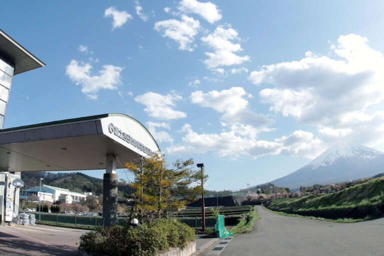 富士山を背景にした施設の外観。周辺環境と建物入口が見える晴天時の撮影。
