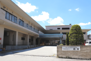 介護施設の建物外観。平屋と2階建ての棟からなり、玄関前に広いアプローチがある